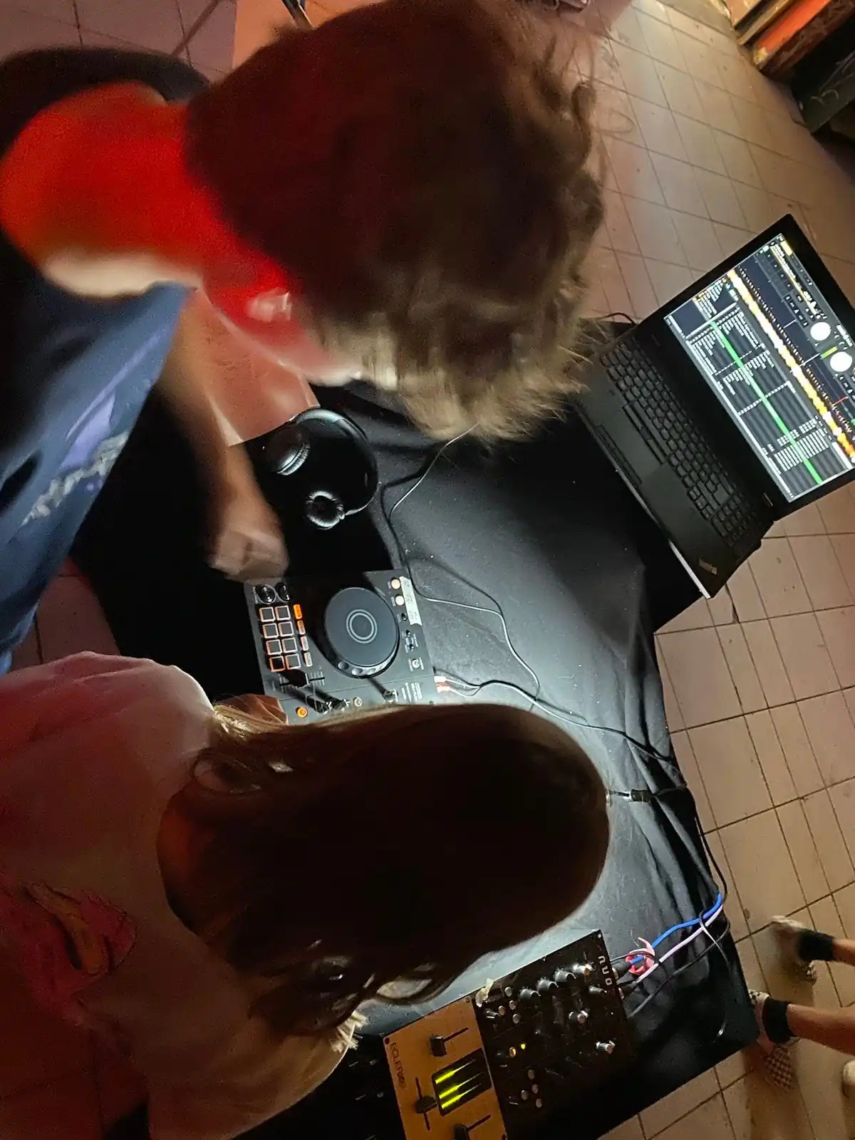 Vor zwei Jugendlichen sind ein Laptop, 1 DJ- und ein Mischpult aufgebaut
